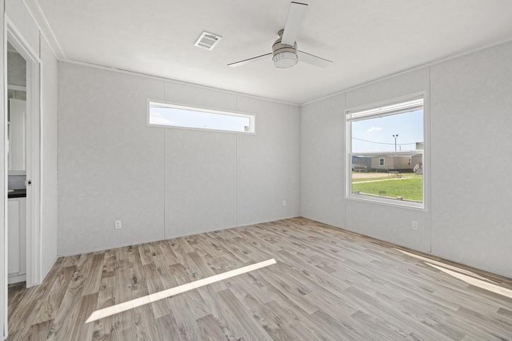 Primary bedroom with ceiling fan and natural light